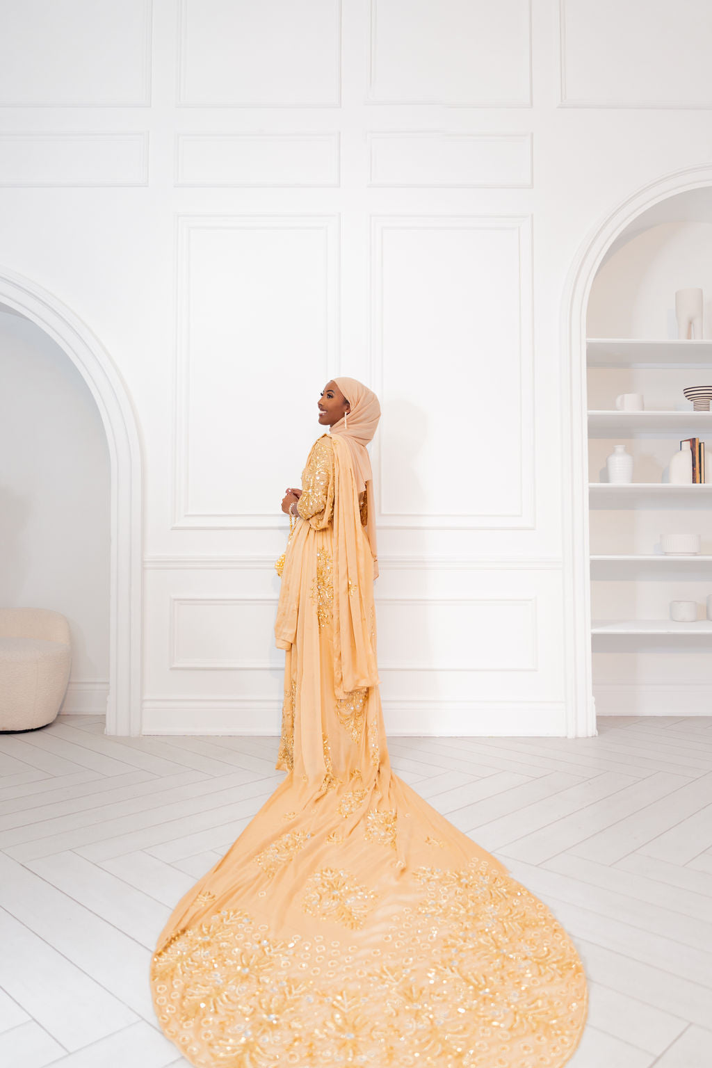 Woman wearing champagne gold Somali bridal/wedding dirac facing away.